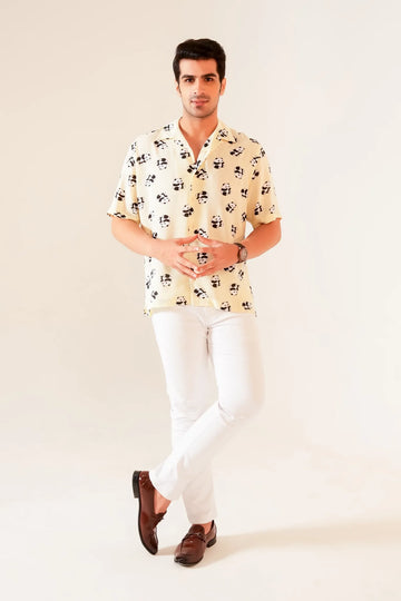 Full front view of man wearing yellow panda print oversized summer shirt styled with white pants and brown loafers