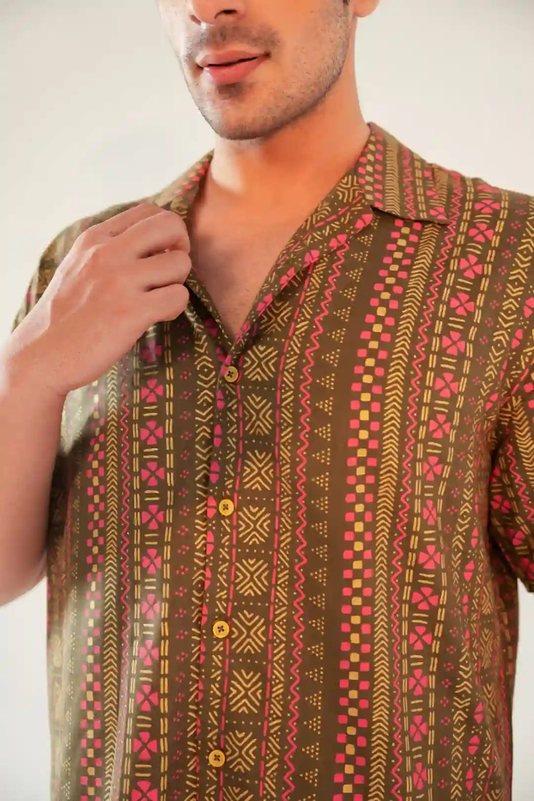 Close-up of camp collar and button-down detail on olive green geometric print rayon shirt