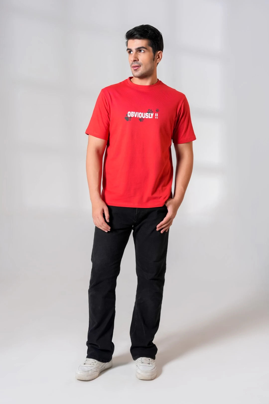 Man standing in a crimson red regular fit cotton t-shirt with bold "Obviously!!" chest print, styled with black jeans and white sneakers