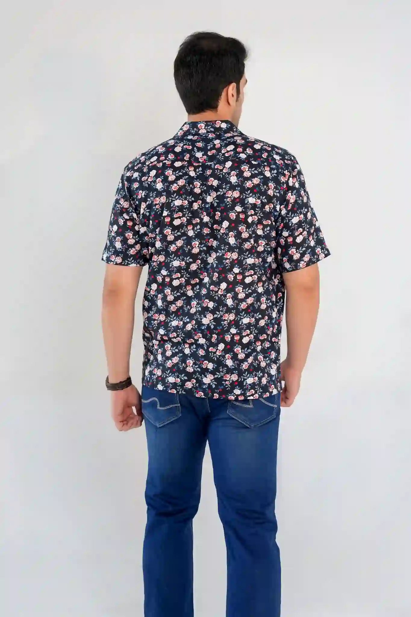 Back view of a man wearing a midnight navy floral shirt with denim jeans, highlighting relaxed fit and floral pattern details