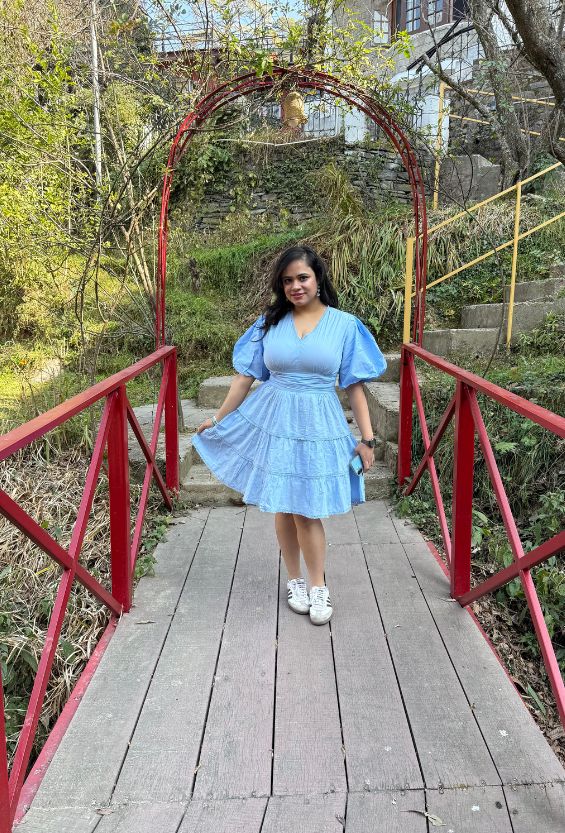 Woman in a blue dress standing on a wooden bridge with a red archway in a natural setting.slider_item_QEWFHC