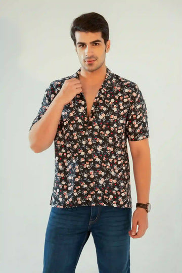 Close-up of a man adjusting the collar of a navy floral shirt paired with denim jeans, showcasing casual summer styling